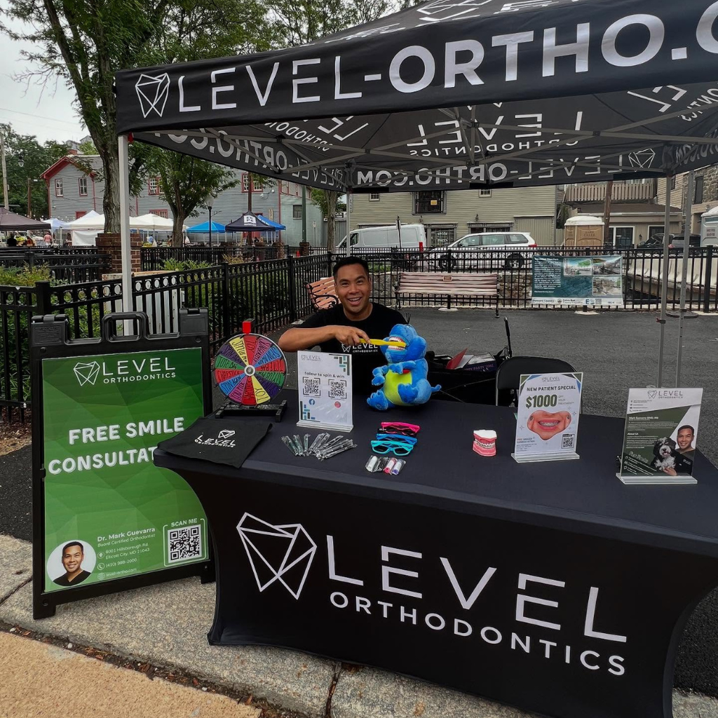 A dentist smiles at a booth under a 